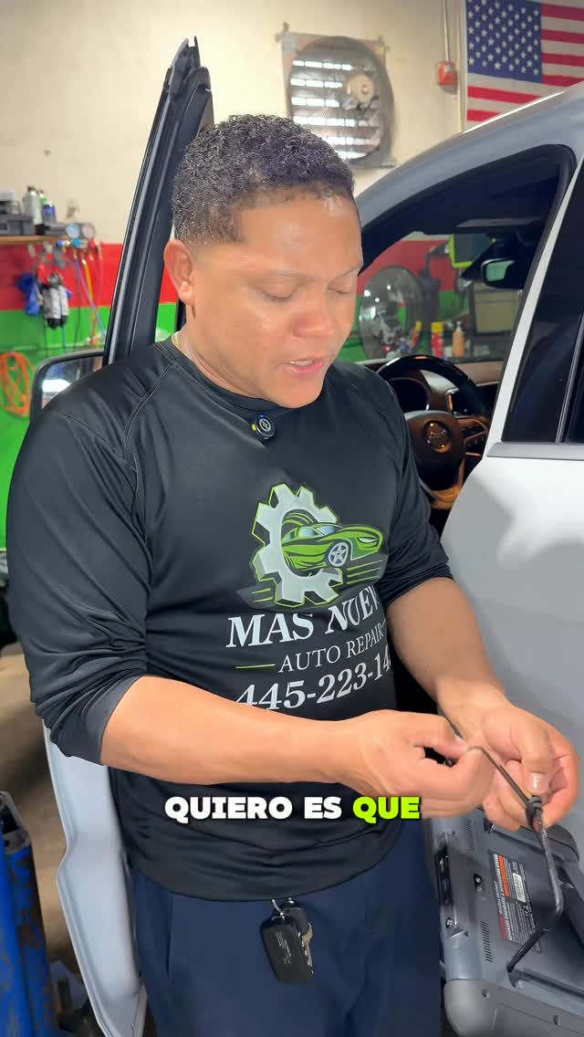 Technician in a Mas Nuevo shirt working beside an open car door