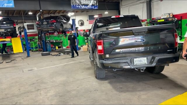 Shop interior with vehicles on lifts and a pickup truck in the bay